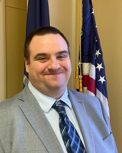 headshot of a man with flags in the background