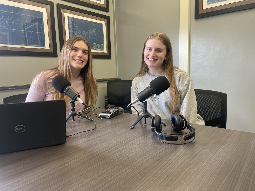 two females sitting together with microphones in front of their faces