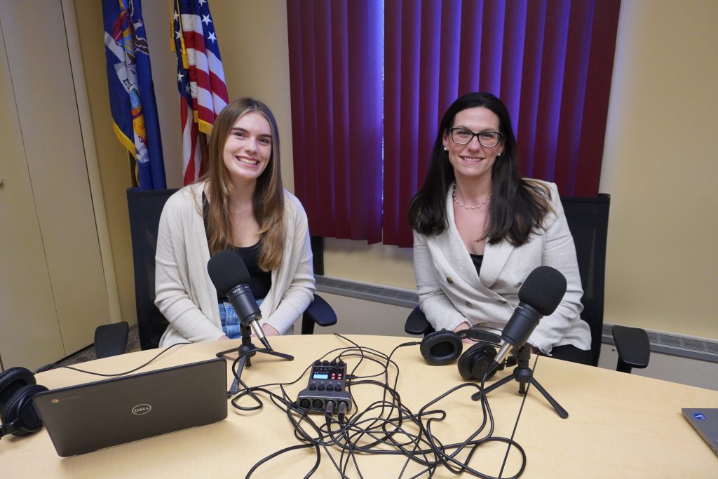 two females posing for a photo with microphones set up in front of them