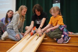 teacher helps students set their cars up on the track.