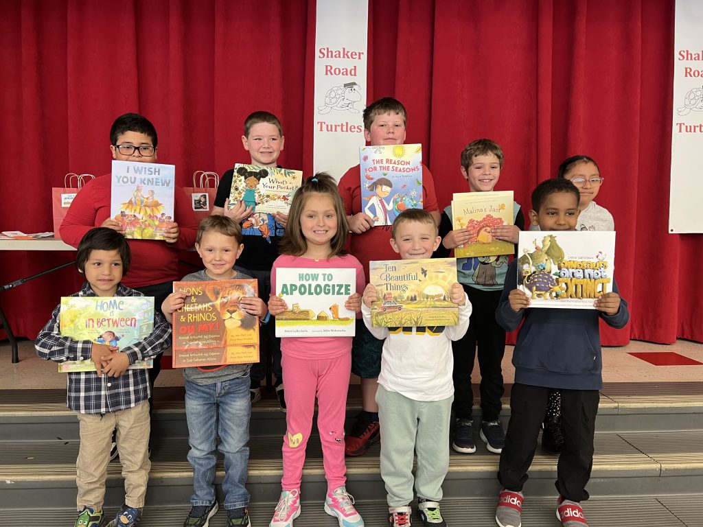 students pose for a photo holding their favorite books proudly.