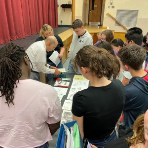 older male interacts with students.