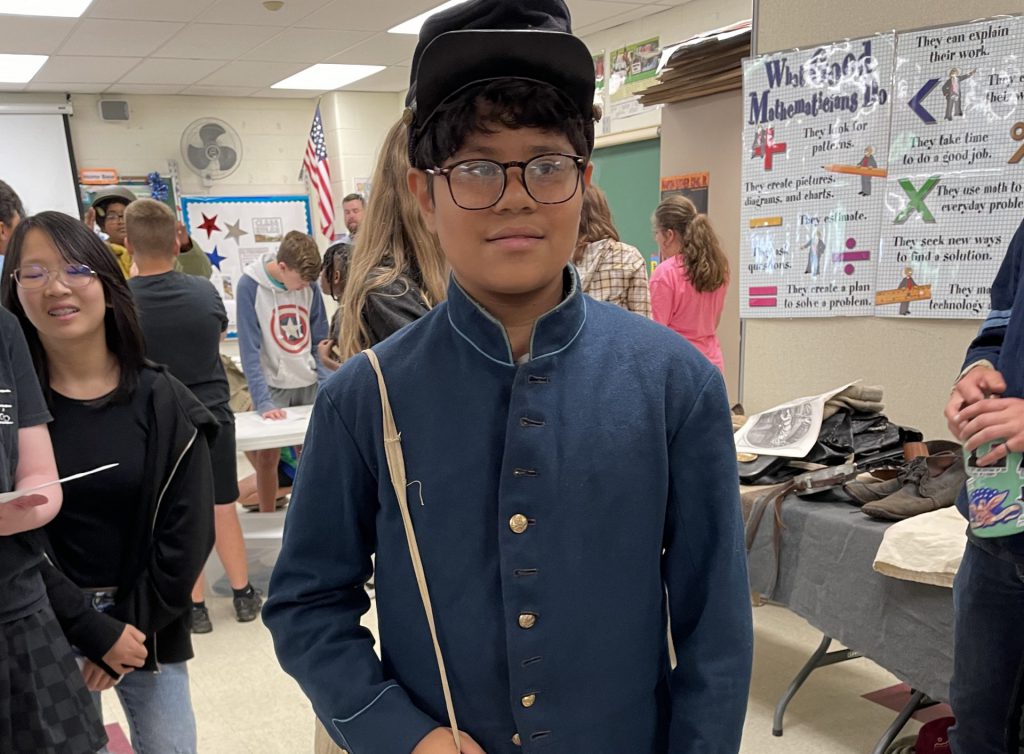 student tries on an old uniform of a soldier