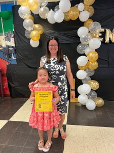 student and teacher pose for a photo. student hold certificate.