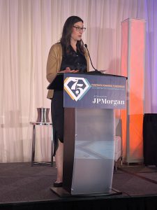 women shares remarks on stage at a conference