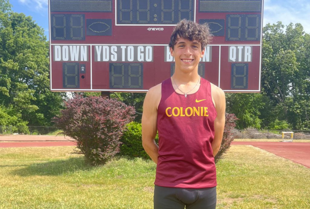 boy track athlete poses for a photo outside.