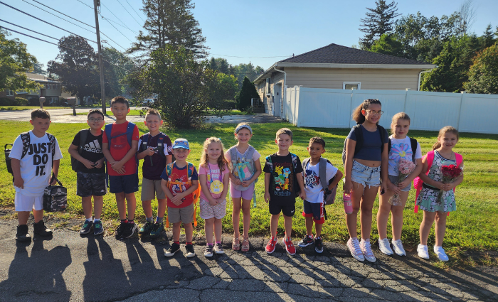 students standing at the bus stop on the first day of school.