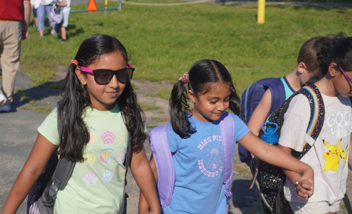 Students hold hands as they walk into school on the first day.