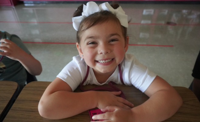 little girl smiles big on her first day of school