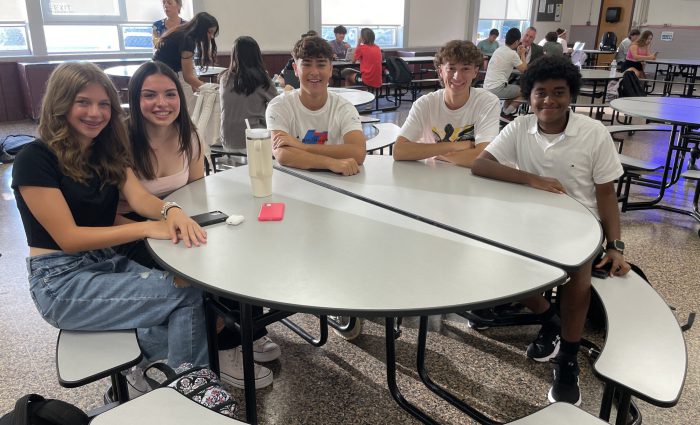 five students sitting at a table together in the cafeteria