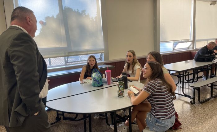 Superintendent talks to four female students in the cafeteria.