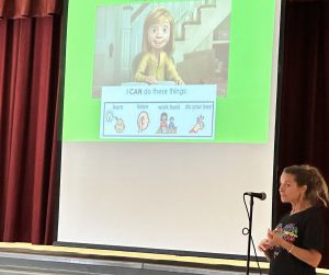 teacher speaks in microphone to students during assembly