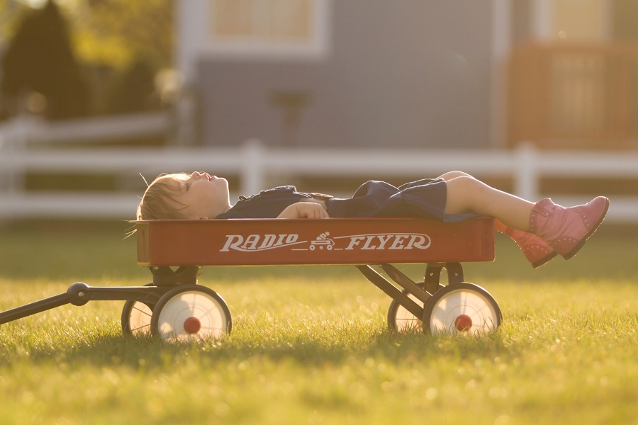 A boy laying in a red wagon A boy laying in a red wagon