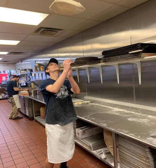 High School student twirling pizza dough