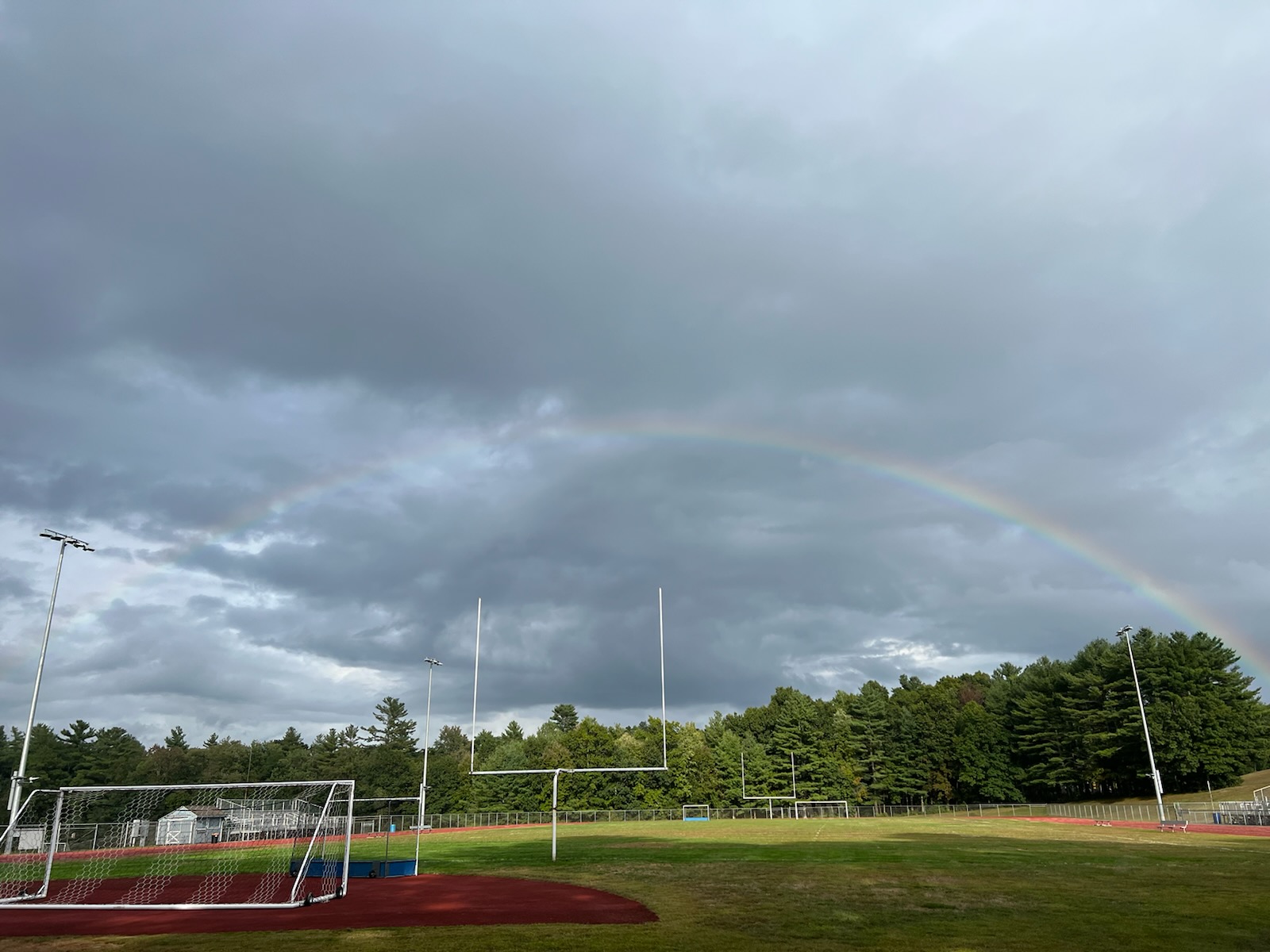 Picture of Stafford High School football field with trees in the background and a rainbow over the field.
