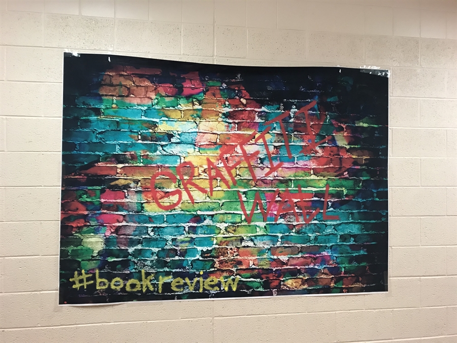 Poster on the wall with all colors painted on it and says graffiti wall.