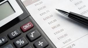 Close up of calculator and pen tip on top of financial report.