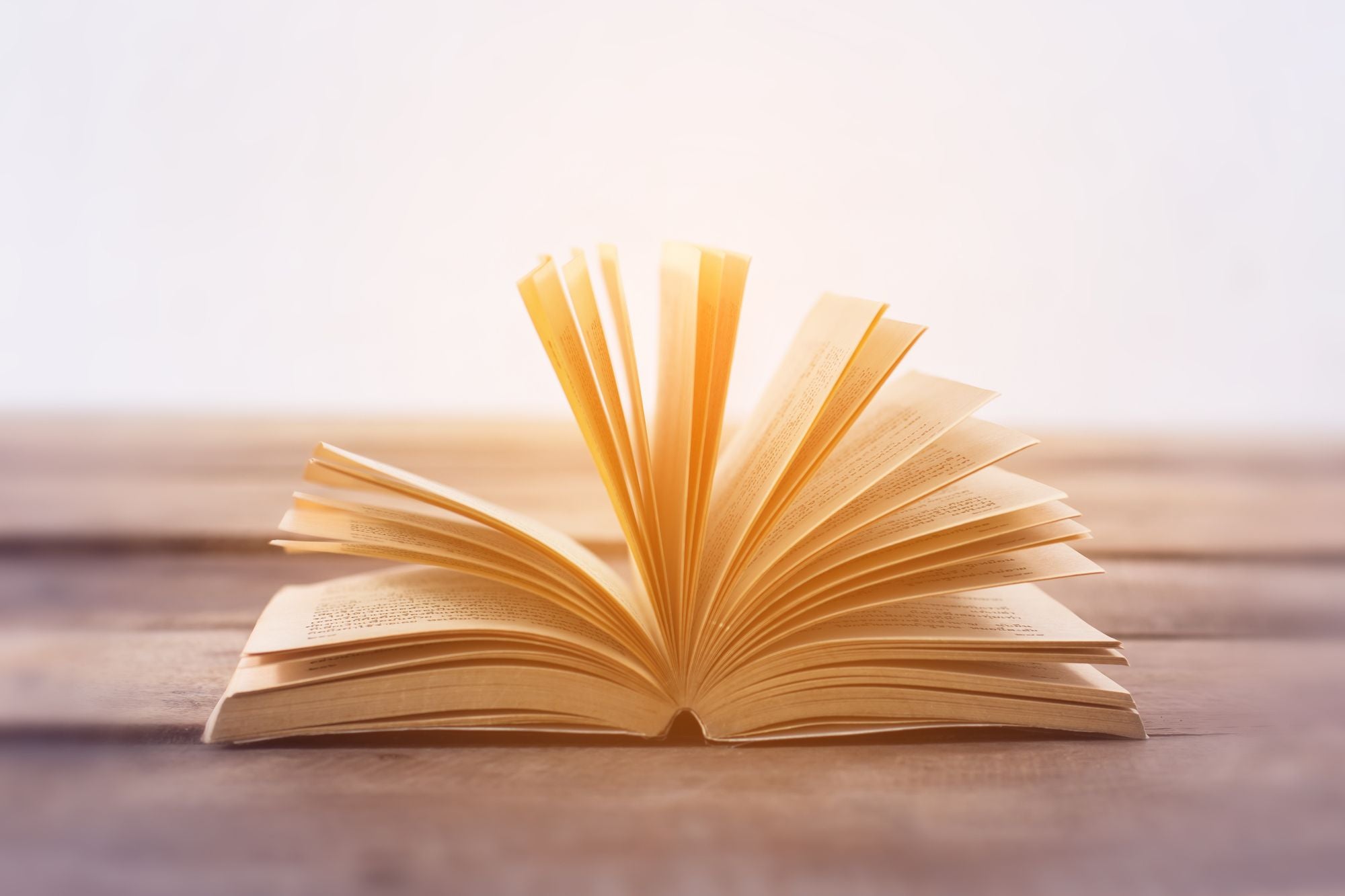 Close up of a book laying open on a wooden table.