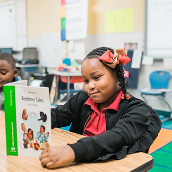 Girl reading book at her desk and smiling