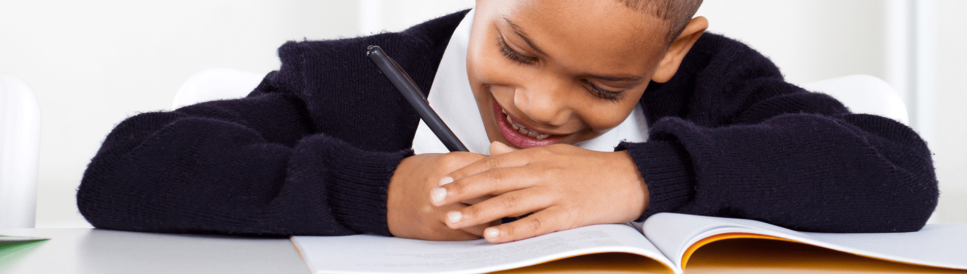 Boy smiling while writing in notebook