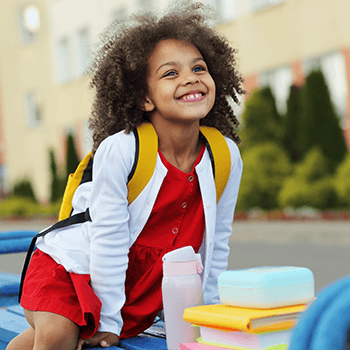 Smiling girl sitting on bench with backpack on