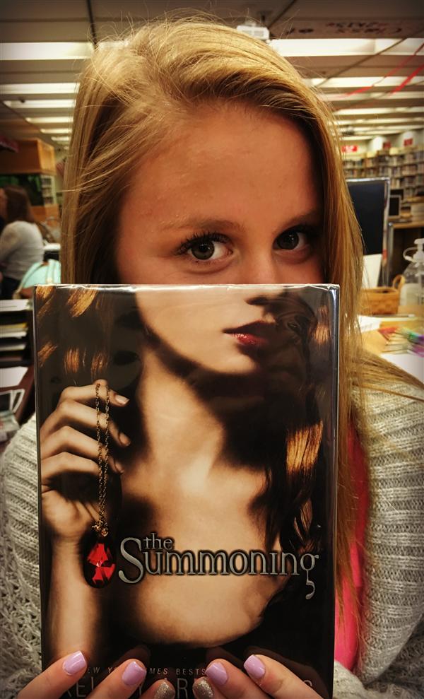 Student showing half her face as the upper half of the face on the book. Book Face