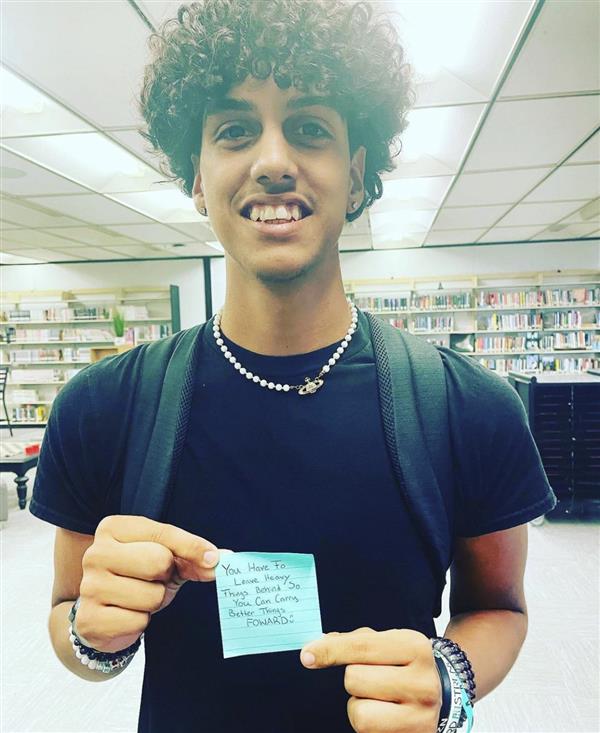 Student holding a positive sticky note