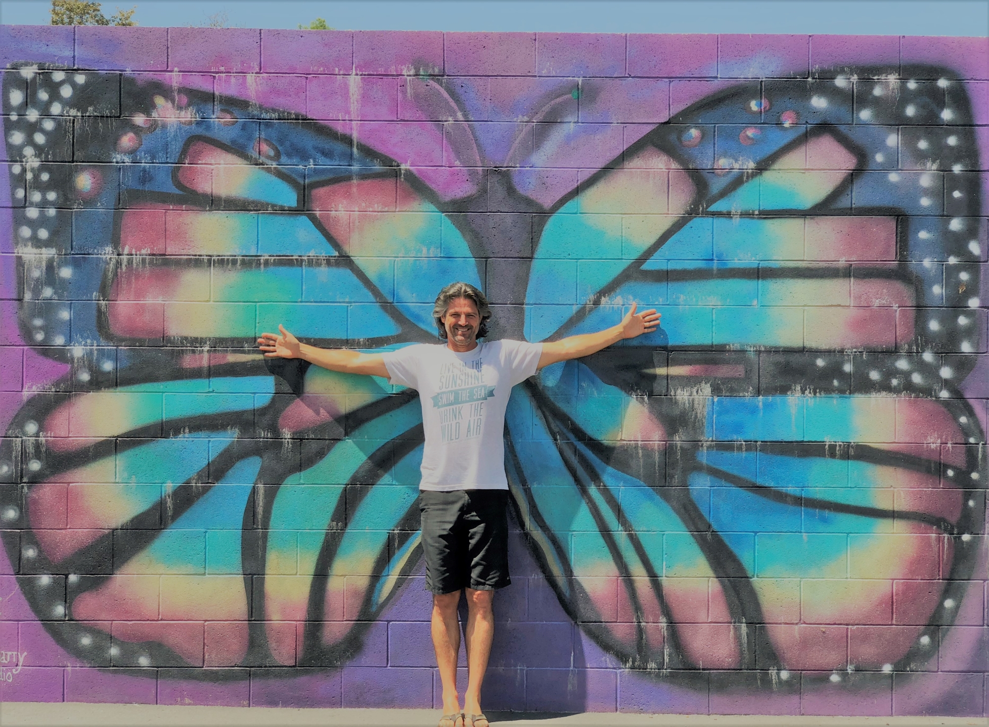 Mr. Retzer standing in front of the butterfly wall on the playground Mr. Retzer standing in front of the butterfly wall on the playground