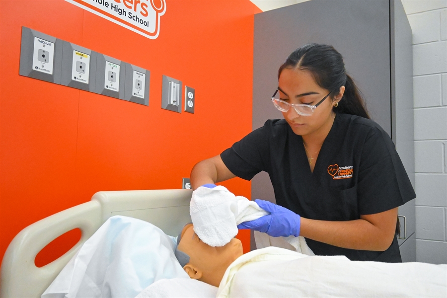 Student in scrubs working in lab