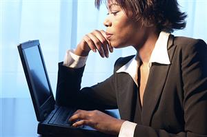 Stylish woman wearing dark colored business attire using a laptop 