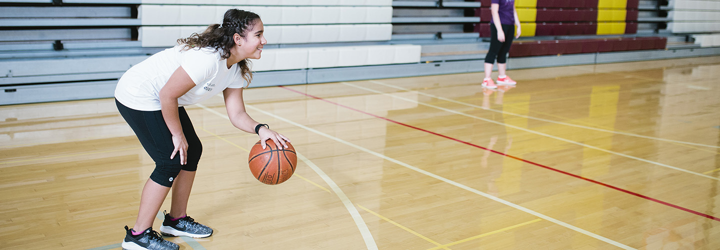 Student playing basketball in PE class