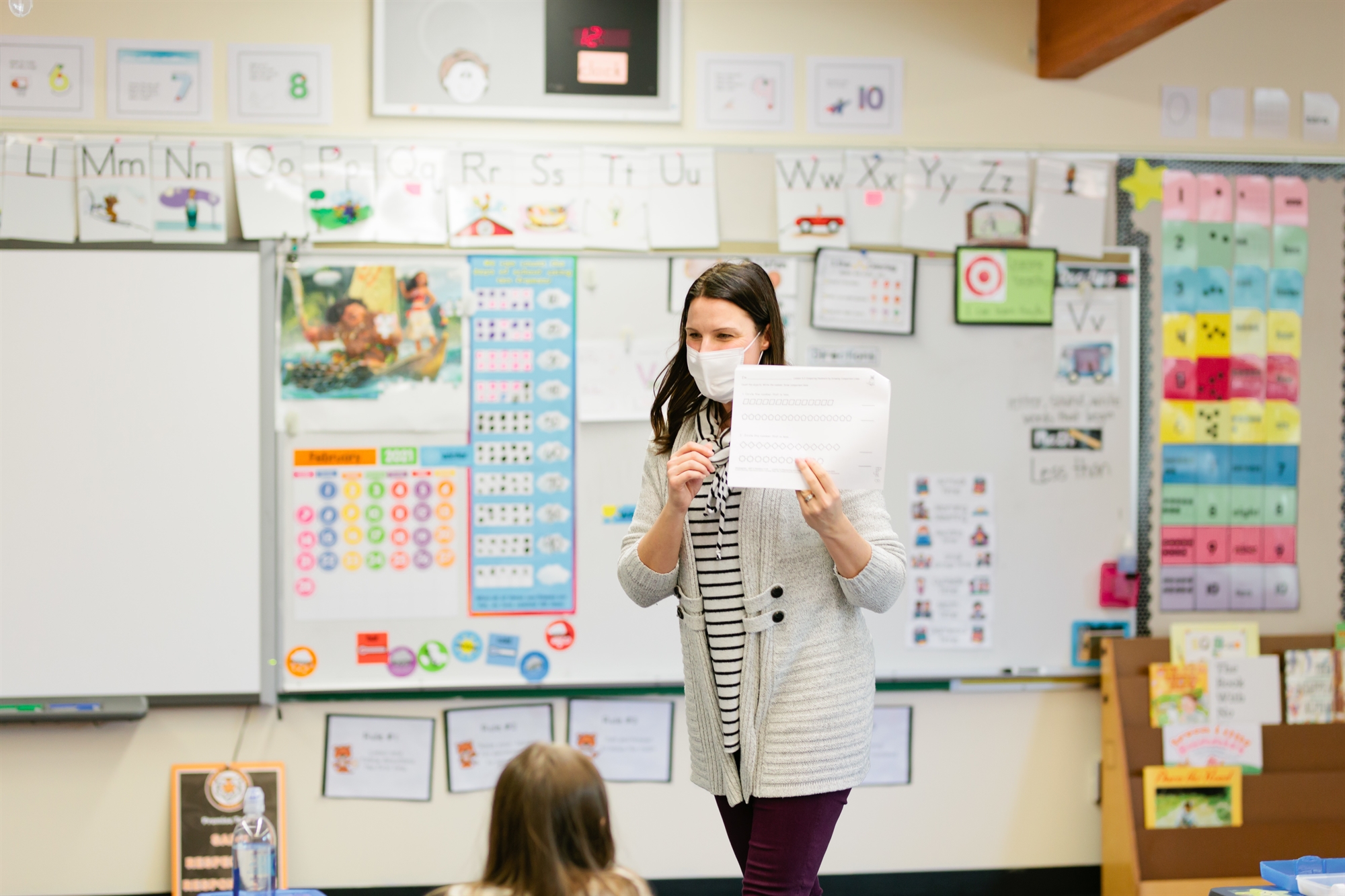 Teacher showing a piece of paper to a classroom