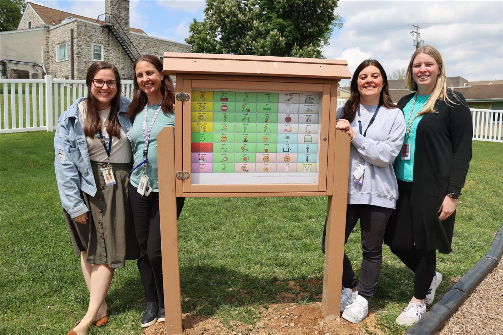 SLP staff posing next to communication board