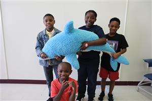 students pose with stuffed dolphin toy