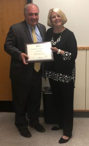 Board of Education president Norman Chirco stands with an award. 