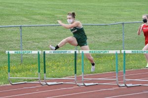 Mariah Quigley leaps over a hurdle in a track meet