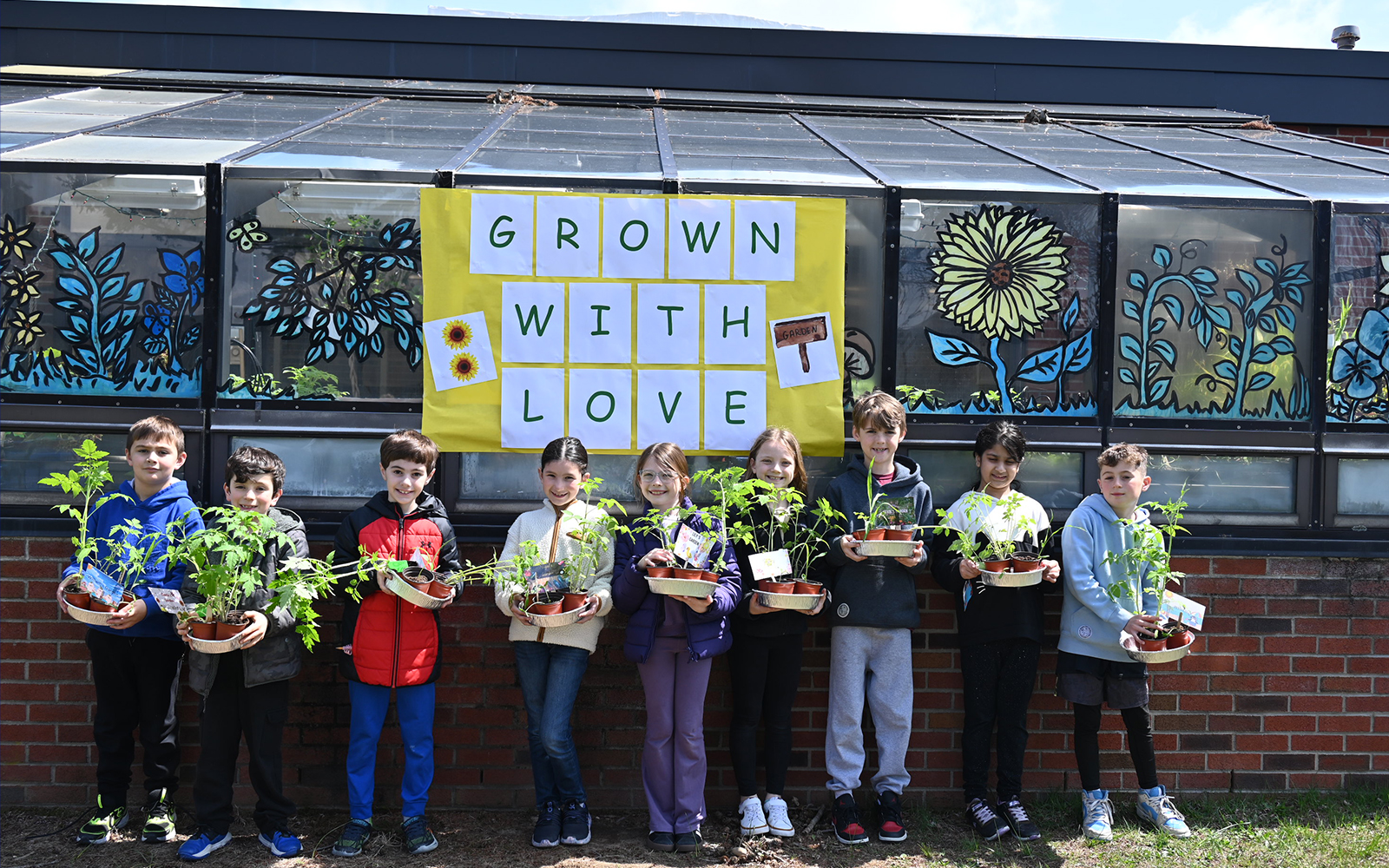 9 students holding plants