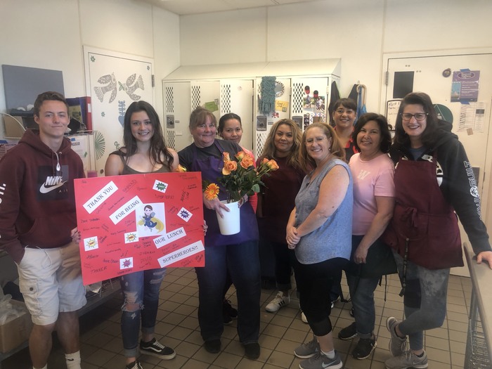 Students giving a poster and flowers to their Food Service Workers