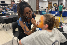 Woman painting a girl's face