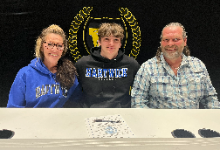RJ Burnett between a man and woman in front of a banner