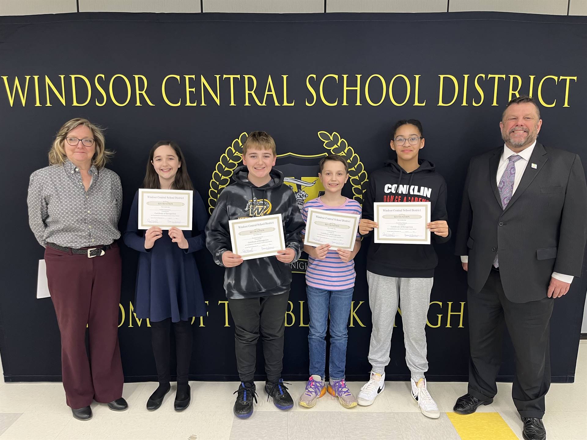 Four children standing between two adults in front of a banner