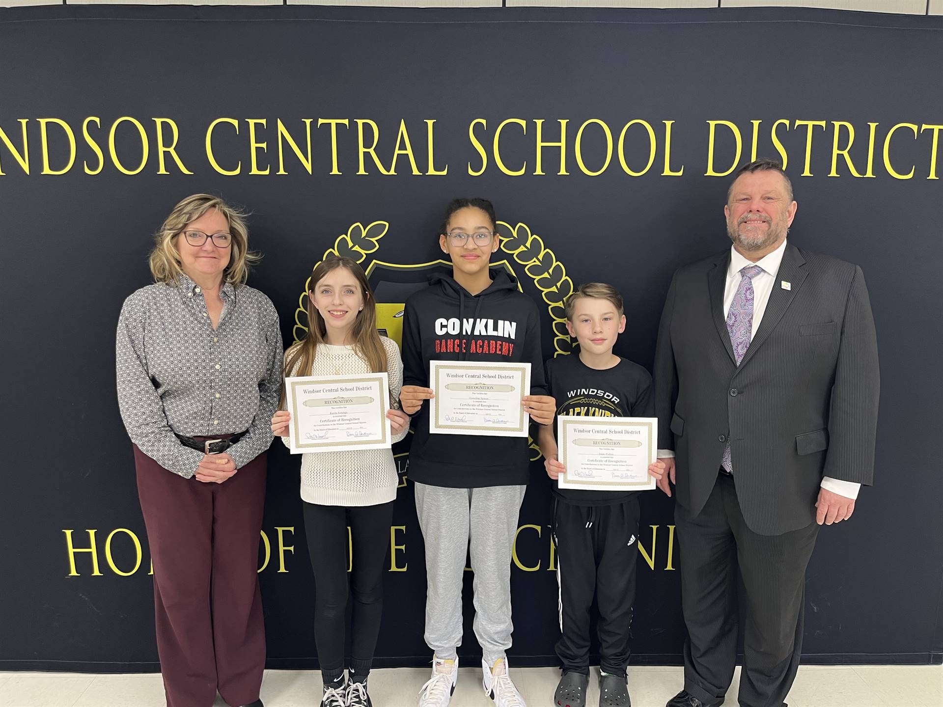 Three children standing between two adults in front of a banner