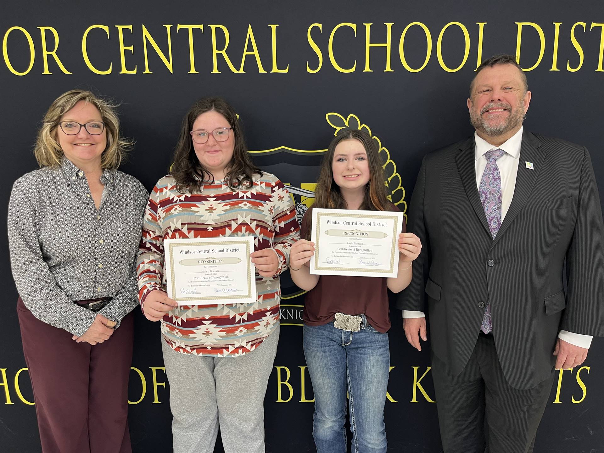 Two girls standing between a man and woman in front of a banner