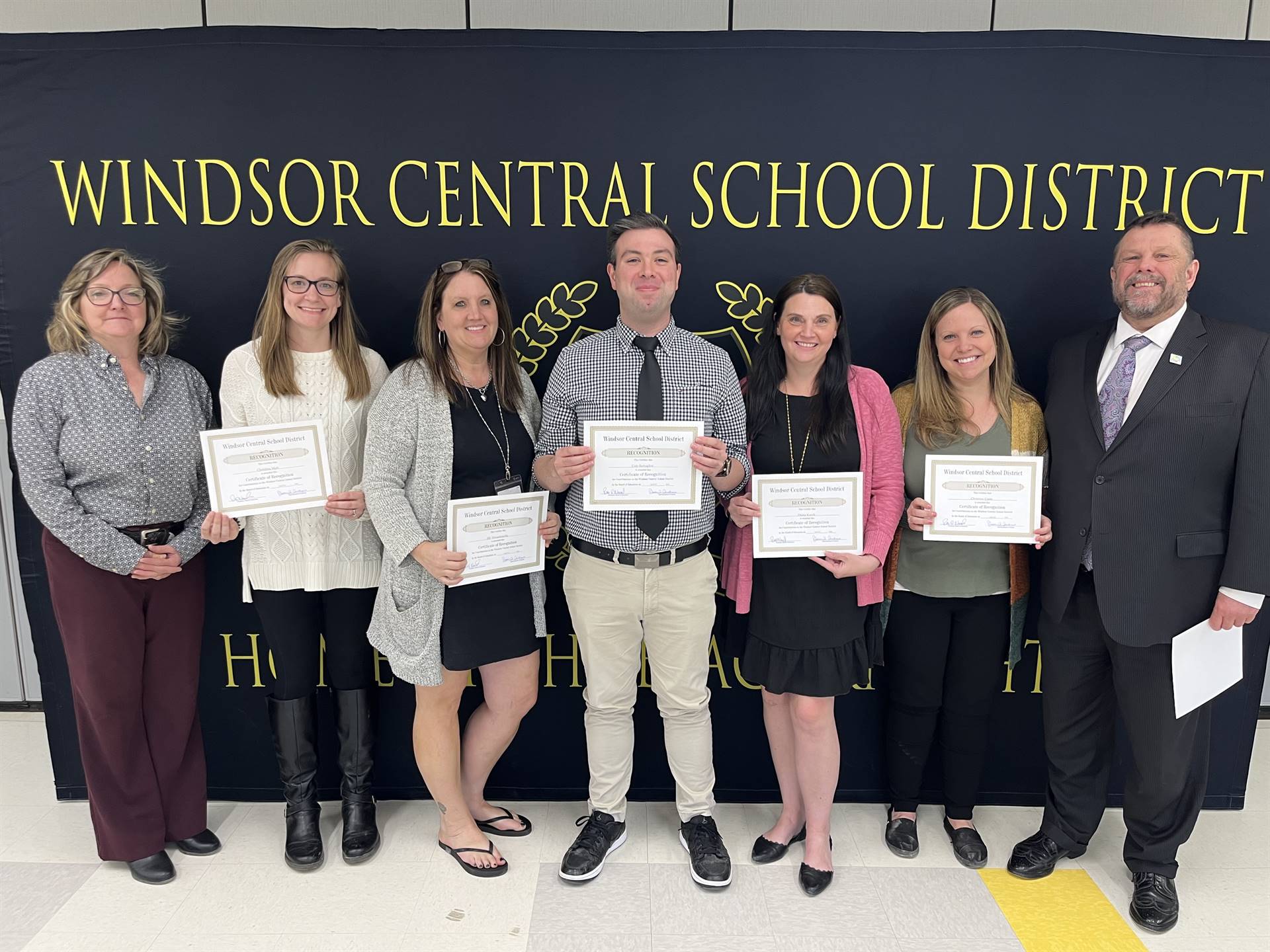 Five women and two men standing in front of a banner