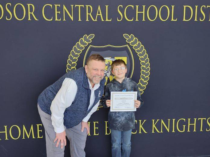A man standing next to a boy in front of a banner