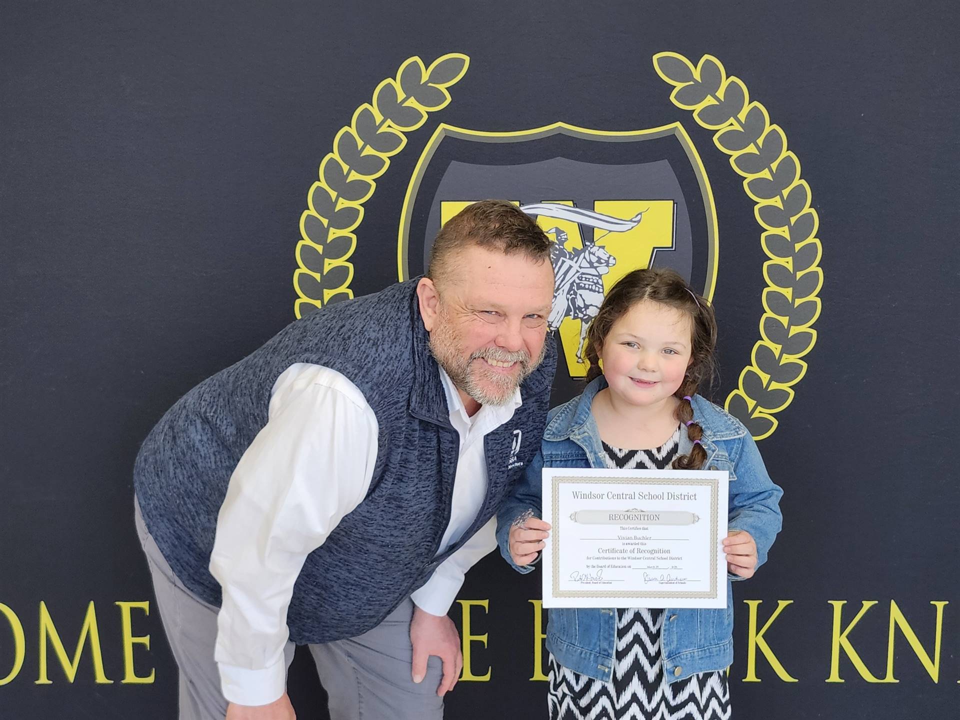 A man and young girl standing in front of a banner. 