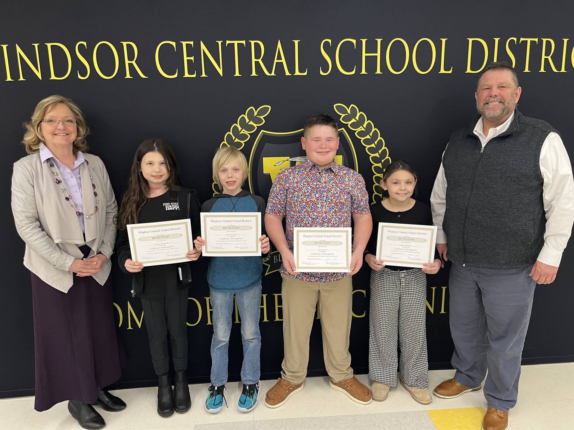Four children standing between a woman and man in front of a banner