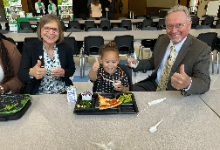 Young girl and two adults giving a thumbs up