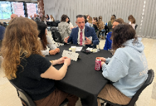 A man sitting at a table with four others
