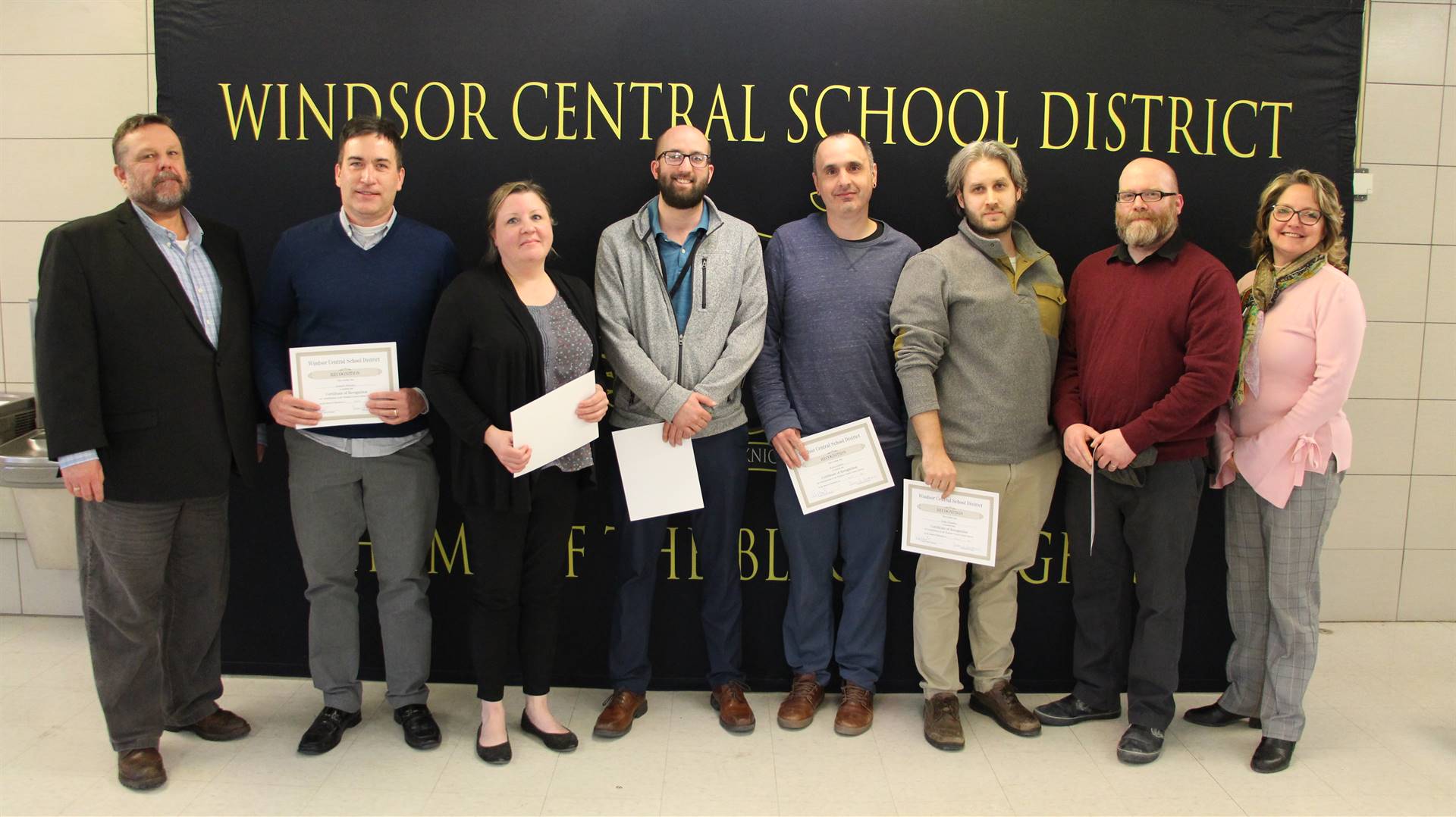 Eight people standing in front of a banner